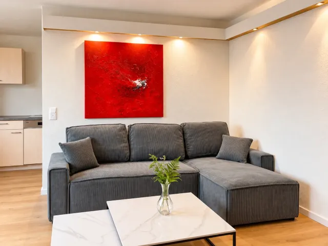Graues Ecksofa unter einem roten Bild im Wohnbereich